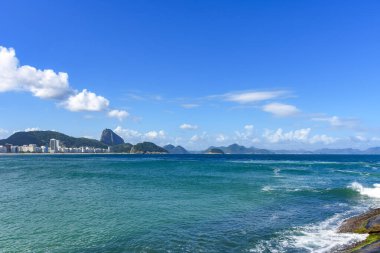 Arka planda Rio de Janeiro tepeleri olan Copacabana sahilinde güneşli bir gün.