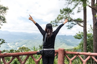Hippi kız sırt çantası zevk ile bir dağın tepesinde günbatımı eşleyin. Bir mockup arka plan Vadisi manzara güneş ışığı seyahat seyahat.