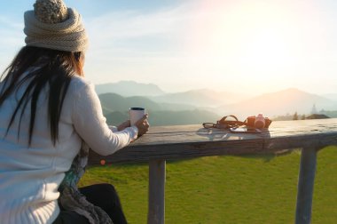 Asyalı kadın kahve ve çay içme gülümseyen ve fotoğraf çekmek ve açık balkon evinde zevk onun sıcak sabah güneş ışığında oturan güneş rahatlayın vintage. Yaşam tarzı kavramı