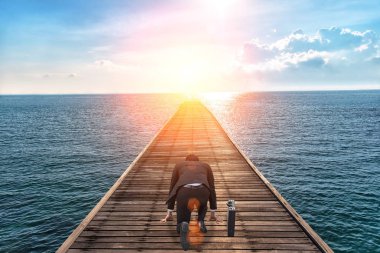 Yarışma hazırlamak için resmi takım elbise ve start hattı üzerinde diz çökmüş işadamı