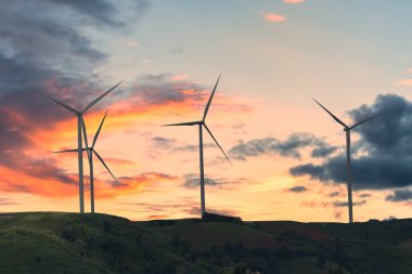 Rüzgar türbininin silueti günbatımında elektrik üretiyor.