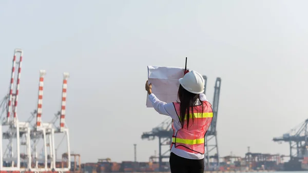 Engineers woman holding radio, blueprint and report schedule for workers security control at power plant energy industry, Engineer Concept,professional,safety,industr