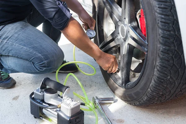 Asiate Überprüft Luftdruck Und Füllluft Den Reifen Seines Autos Stockbild