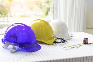 Güvenlik kask ve inşaat alanı, Emanet kask beyaz, mavi ve sarı foreman/mühendis/mimar/ziyaretçi kullanılmak üzere şantiye güvenliği için masada plan iş, işçi, sanayi