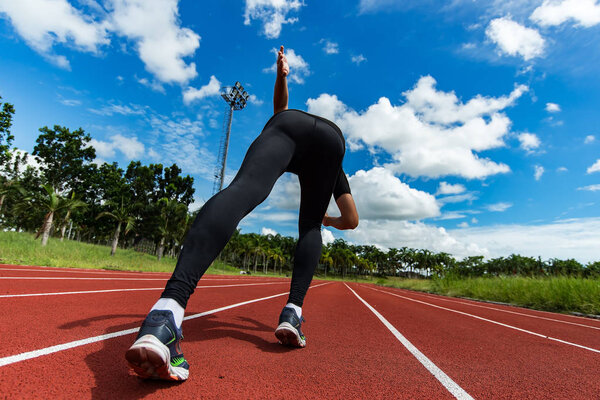 young muscular athlete is at the start of the treadmill at the stadium