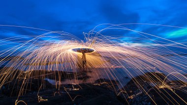 Showers of hot glowing sparks from spinning steel wool on the rock and beach clipart