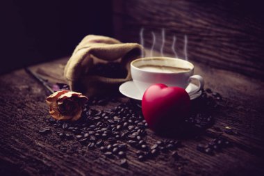 Kahve fincanı ve masada gül desenli kahve çekirdekleri