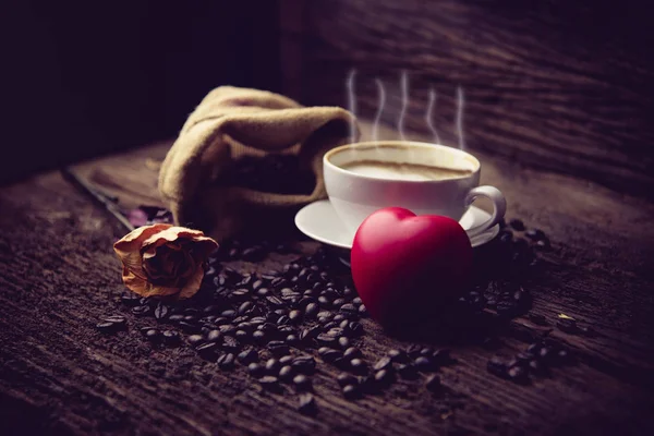 Kahve fincanı ve masada gül desenli kahve çekirdekleri