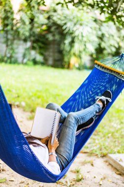 genç kadın hamakta yatan bir kitap okuma