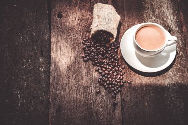 kahve fincanı ve masada kahve çekirdekleri