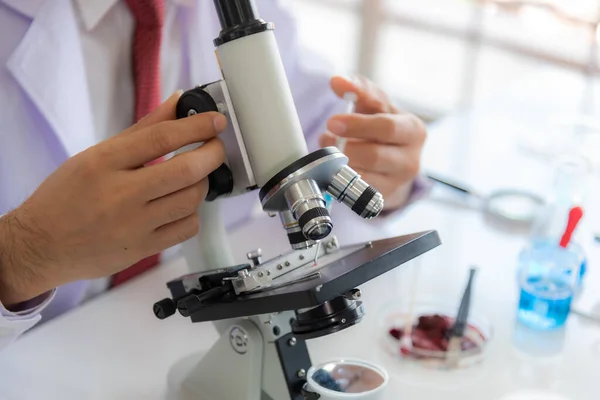 Yakın plan: kovid 19 örneğini mikroskop ile analiz eden ve elinde Coronavirus covid 19 kan örneği bulunan bilim adamı kadın.