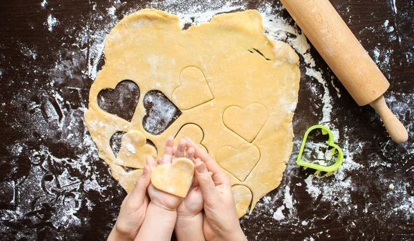 Hands of woman and child made from dough heart. Cooking, flour