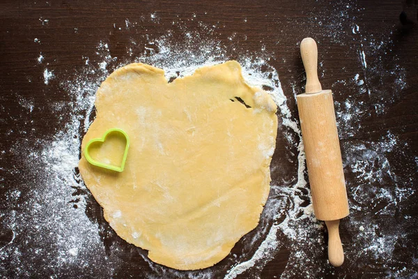 Roll out the dough on a black table. Cooking, flour, rolling pin