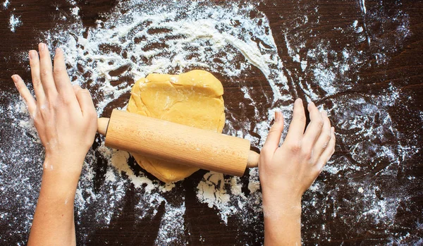 Womans hands roll the dough. Protection, heat comfort.