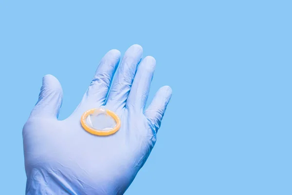 Guante de mano sosteniendo un condón. Médico y anticonceptivos —  Fotos de Stock