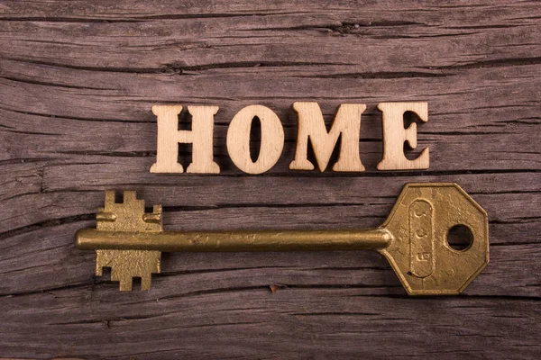 Word thuis gemaakt van houten letters met een sleutel — Stockfoto