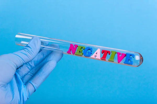 Word negative in test-tube holding a gloved hand — Stock Photo, Image