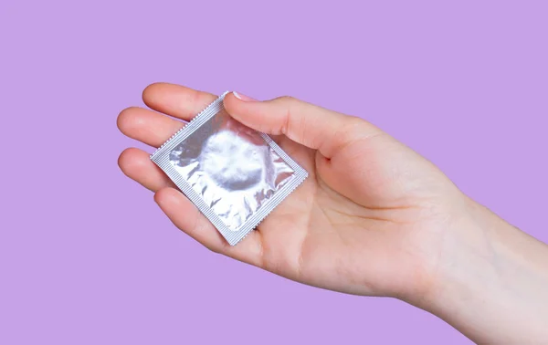 Handen håller i en kondom — Stockfoto
