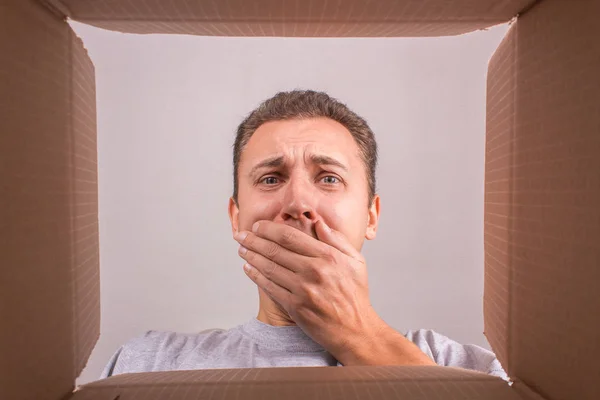 Man frightened, unpacking and opening a carton gift box, and loo