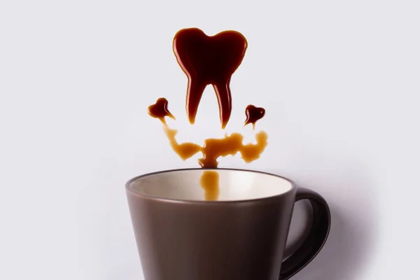 Coffee in the form of a tooth. A cup of coffee and spilled coffe — Stock Photo, Image