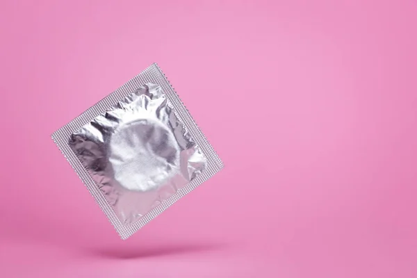 Saco de preservativo em levitação de ar em um fundo rosa. Espaço vazio para texto. mock-up — Fotografia de Stock