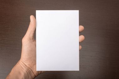 Gri bir arka plan üzerinde elinde boş kartpostal. Broşür A6 mockup