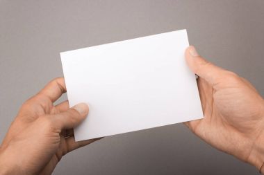 Gri bir arka plan üzerinde elinde boş kartpostal. Broşür A6 mockup