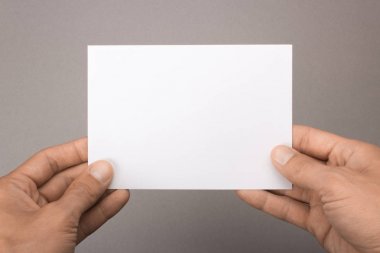 Gri bir arka plan üzerinde elinde boş kartpostal. Broşür A6 mockup