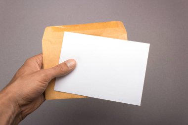 Boş kartpostal ve el gri bir arka plan üzerinde zarfta. Leafle