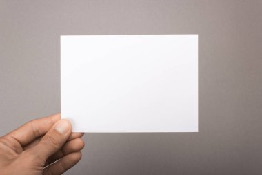 Gri bir arka plan üzerinde elinde boş kartpostal. Broşür A6 mockup