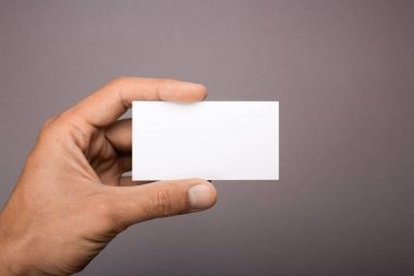 Gri bir arka plan üzerinde elinde boş kartvizit. mockup