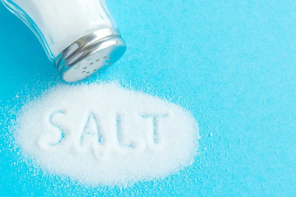 Wort Salz in Salz geschrieben. Schriftzug. zerbröseltes Salz auf blauem Ba — Stockfoto