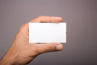 Gri bir arka plan üzerinde elinde boş kartvizit. mockup
