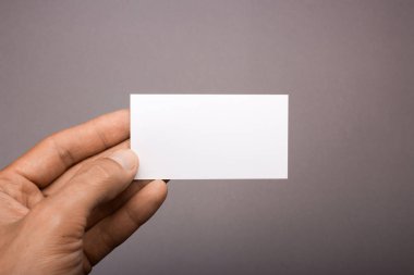 Gri bir arka plan üzerinde elinde boş kartvizit. mockup
