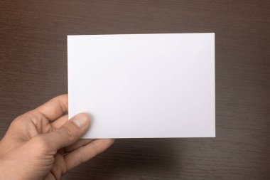 Gri bir arka plan üzerinde elinde boş kartpostal. Broşür A6 mockup