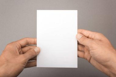 Gri bir arka plan üzerinde elinde boş kartpostal. Broşür A6 mockup