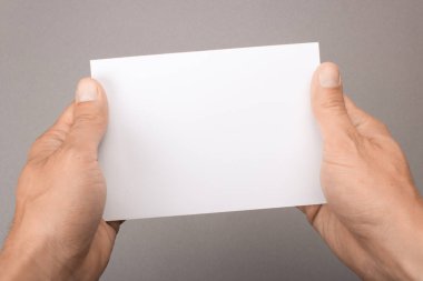 Gri bir arka plan üzerinde elinde boş kartpostal. Broşür A6 mockup