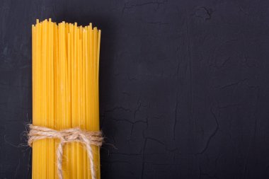 Siyah bir zemin üzerine çiğ sarı uzun spagetti yığını. Kopya S