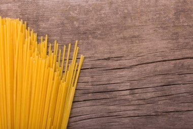 Eski bir ahşap zemin üzerine çiğ sarı uzun spagetti yığını. 