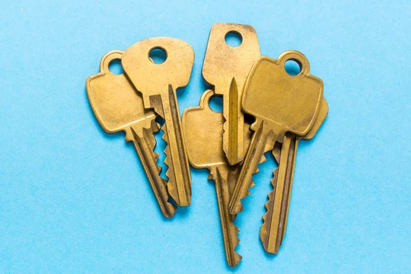 Um monte de chaves douradas está em um fundo azul — Fotografia de Stock