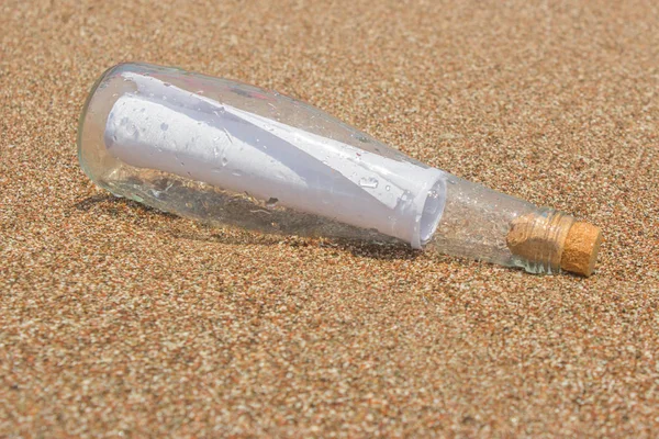 Paper Message in a glass bottle with a cork on the sand. A note on salvation, please help