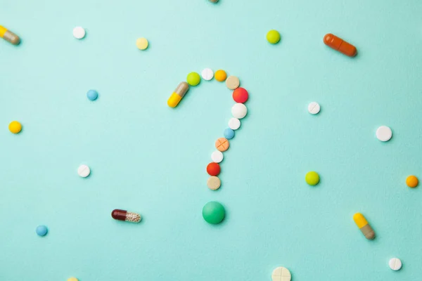 Simbolo punto interrogativo da compresse e capsule colorate su sfondo verde. Quali farmaci scegliere meglio, cosa aiuterà — Foto Stock