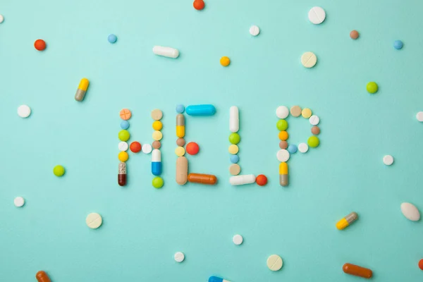 Palabra AYUDA de píldoras y cápsulas de color sobre un fondo verde. Qué medicamentos elegir mejor, qué ayudará — Foto de Stock