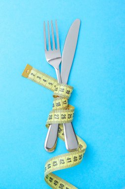 Japon diyeti kilo kaybı için. Çatal ve bıçak sarı mavi arka plan kasette ölçme sarılır