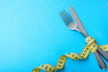 Paleo diyet kilo kaybı için. Çatal ve bıçak sarı mavi arka plan kasette ölçme sarılır