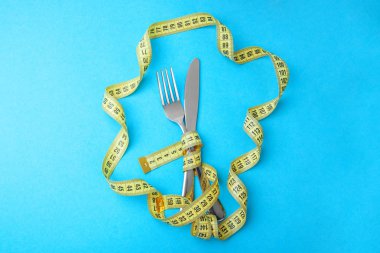 Bitkisel diyet kilo kaybı için. Çatal ve bıçak sarı mavi arka plan kasette ölçme sarılır