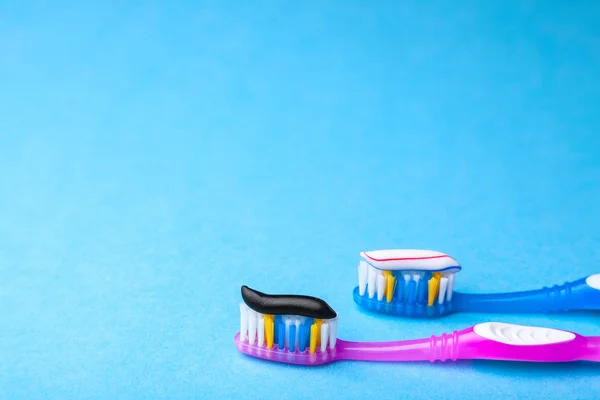Whitening toothpaste is usual colored and black from charcoal on toothbrush. Concept. Which toothpaste to choose? How to whiten your teeth? Copy space for text — Stock Photo, Image