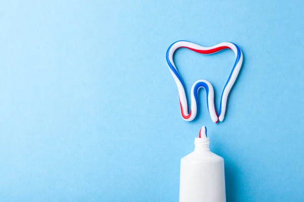 Tooth-paste in the form of tooth. Tube of the paste on blue background. Refreshing and whitening toothpaste. Copy space for text