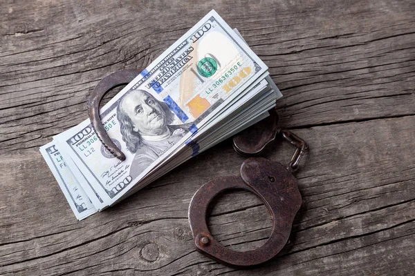 Bribe, money and handcuffs on  wooden table. Theft of official money from the country's budget, concept — Stock Photo, Image