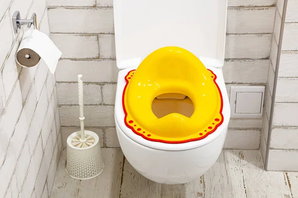 Žluté víko na záchodové prkýnko pro děti. Jak přivyknout dítě na záchod. Bílá koupelna. — Stock fotografie